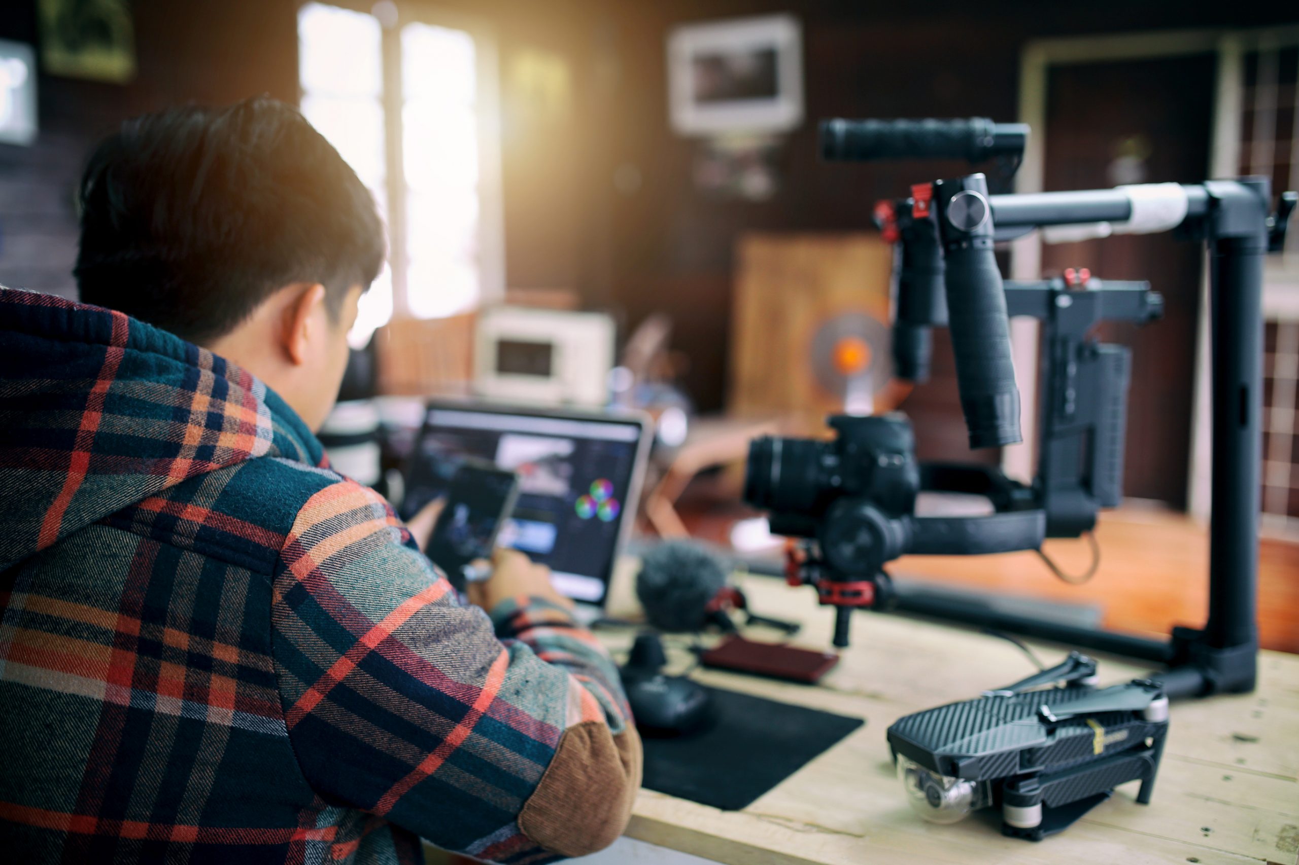 Freelancer man editing video on a laptop and checking smartphone for uploading video to internet online or social media